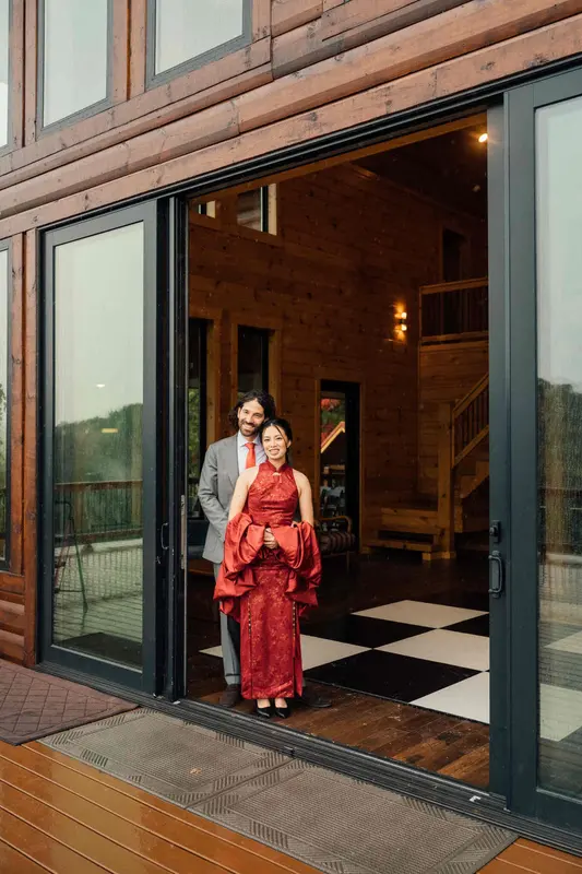 A couple in a red dress and a light suit standing in the open glass doorway of the great room