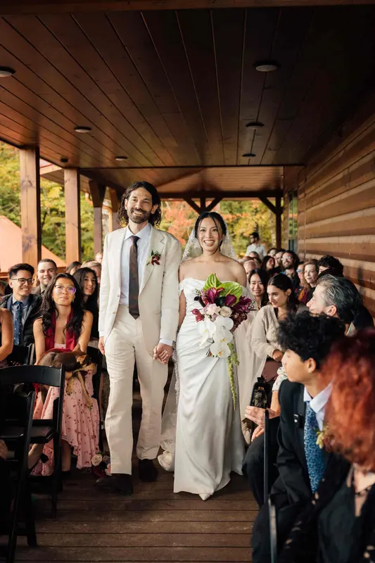 The newlyweds walking down the covered porch between rows of guests