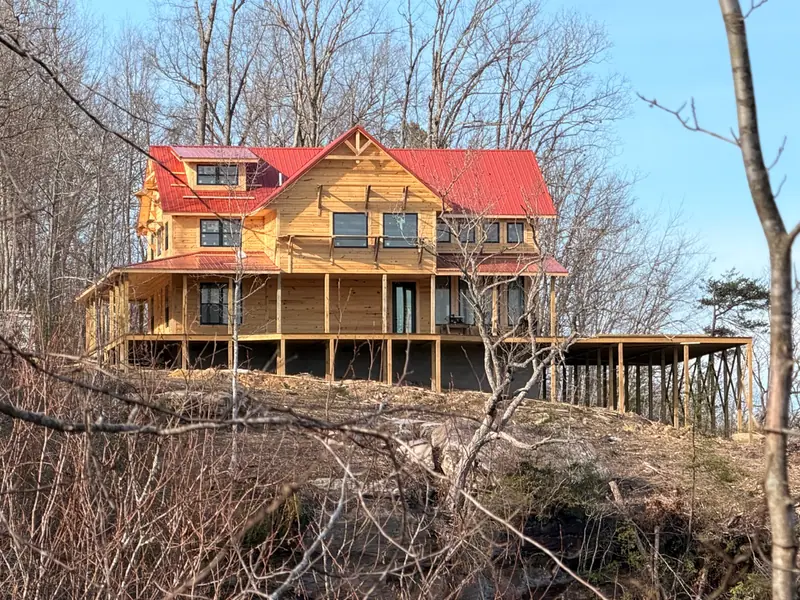 Red River Château under construction at the edge of a cliff, framed by bare winter trees