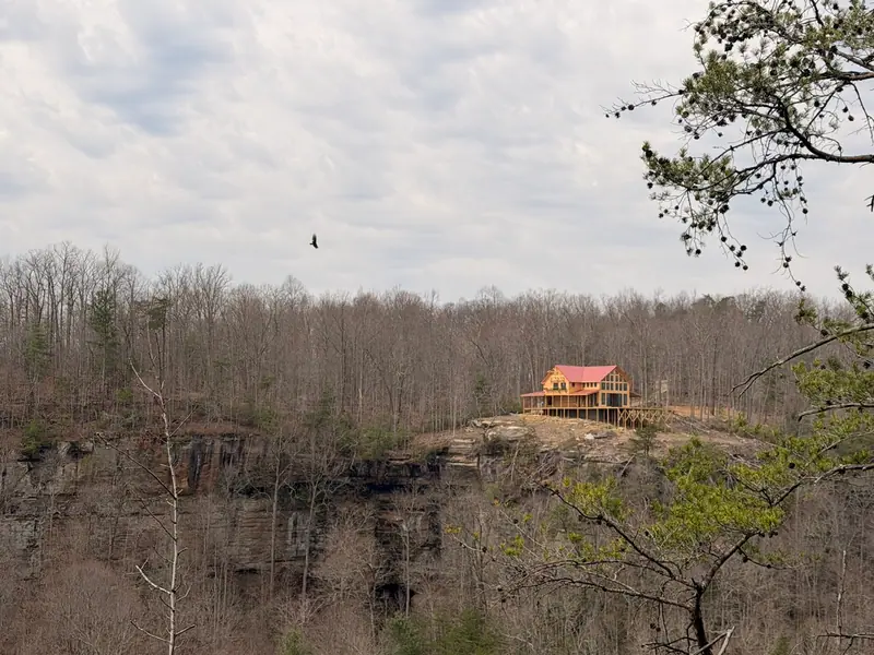 Red River Château seen from across the gorge, sitting on a cliff-top above sandstone walls and bare winter forest