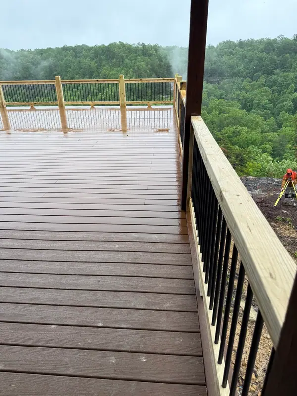Wet deck boards and railing leading toward a forested gorge with low morning mist
