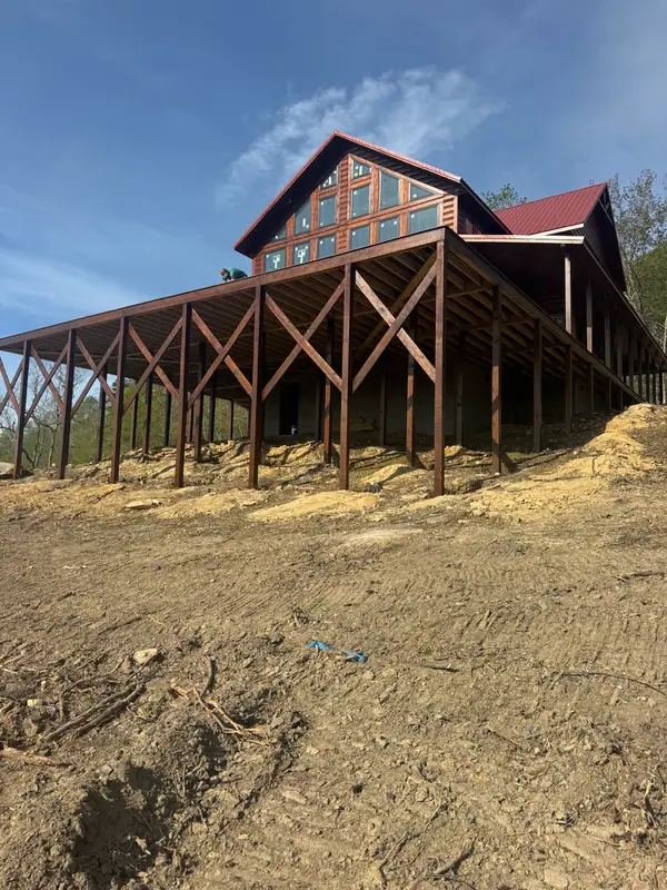 Looking up at Red River Château's elevated deck on timber posts and its tall glass gable wall