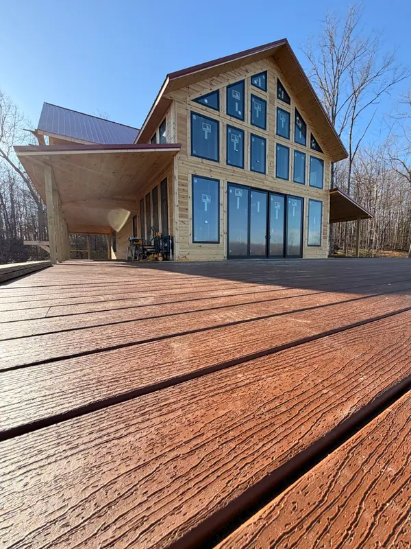Low view across new deck boards toward Red River Château's tall glass gable windows