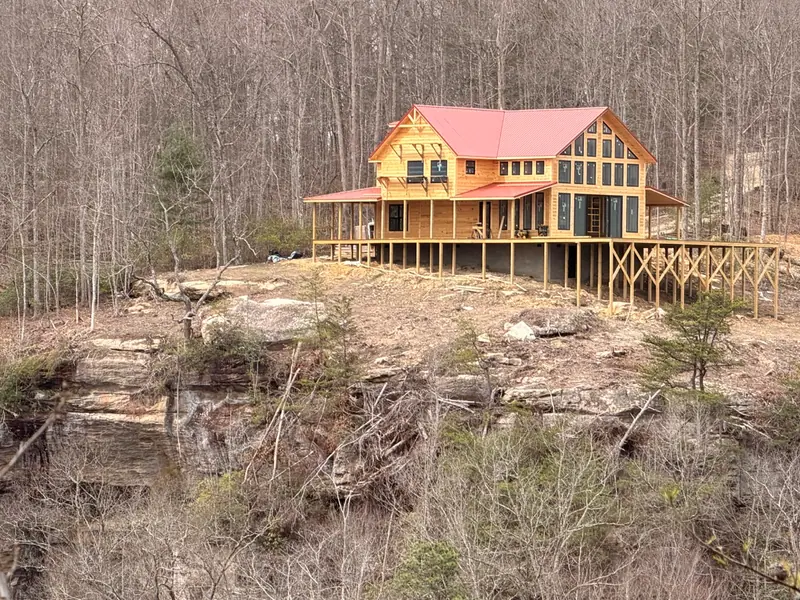 Red River Château on a sandstone rock outcrop with a long deck, surrounded by winter hardwoods