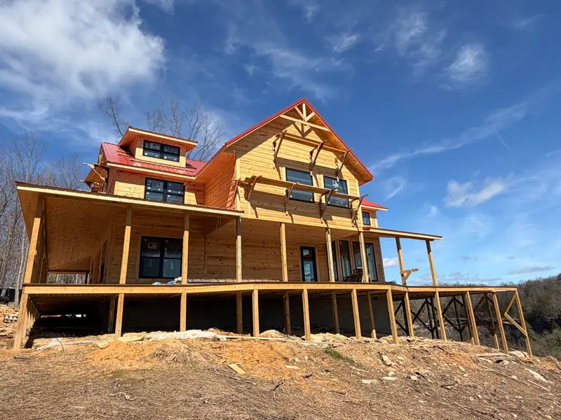 The wraparound porch and gabled roofline of Red River Château during construction